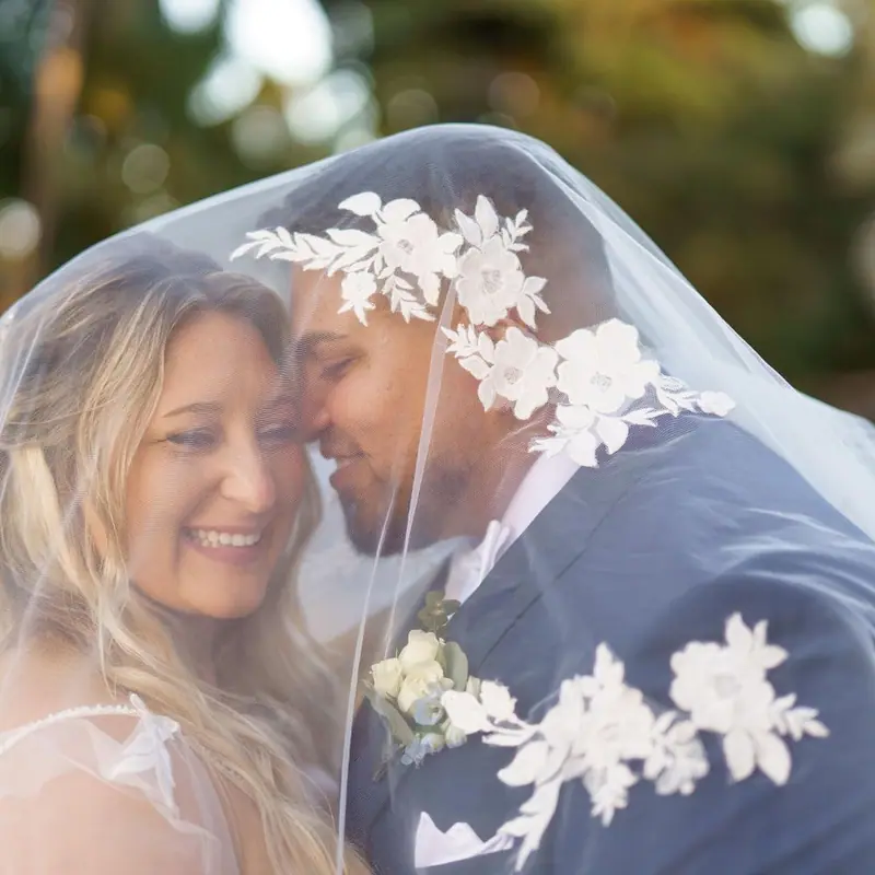 A bride and groom smile together under her lace-trimmed veil