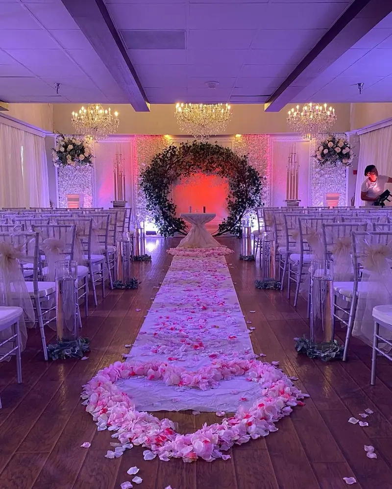 A ceremony aisle lined with rose petals and a petal heart, leading to a floral arch
