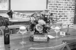Black-and-white photo of a reception table with a flower centerpiece and a reserved sign