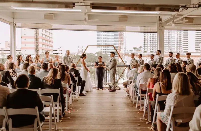 Guests watch a ceremony on a covered terrace overlooking city buildings