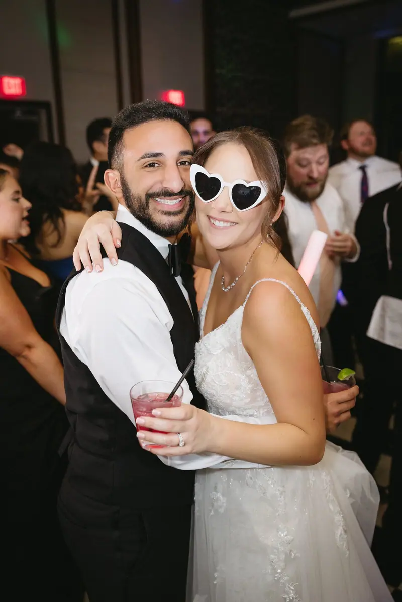 Amanda & Michael celebrating at their reception, the bride in heart-shaped sunglasses