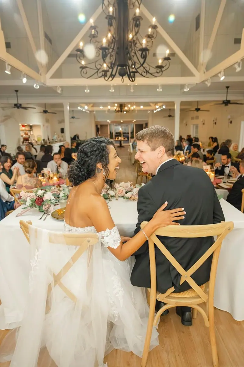 Cintia & Jon sharing a laugh at their reception table
